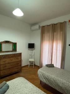 a bedroom with two beds and a dresser and a television at Casa Alighieri in Montalto Uffugo