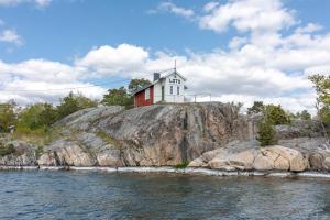 a house on top of a hill next to the water at Sävö Vandrarhem & Café in Västerljung