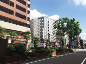 una calle de ciudad vacía con un edificio blanco alto en HOTEL MYSTAYS Yokohama Kannai en Yokohama