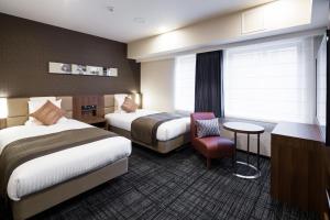 Pokój hotelowy z 2 łóżkami i krzesłem w obiekcie HOTEL MYSTAYS Yokohama Kannai w mieście Jokohama