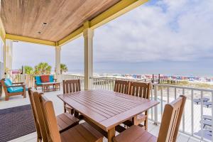 a porch with a wooden table and chairs and the beach at Summer Salt West by Youngs Suncoast in Orange Beach