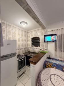 a kitchen with a refrigerator and a tv on the wall at Casa de Praia Bertioga-Costa do Sol Guaratuba in Bertioga