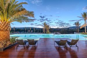 a resort with a pool with chairs and a palm tree at PYRENÉUS RESIDENCE GAV Resorts in Pirenópolis