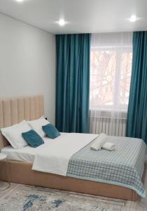 a bedroom with a bed with blue curtains and a window at Абая in Temirtaū +22 photos