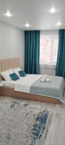a bedroom with a bed with blue curtains and a window at Абая in Temirtaū