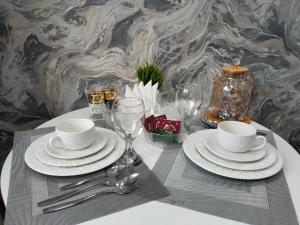 a table with white plates and cups and silverware at Абая in Temirtaū