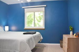 a blue bedroom with a bed and a window at Exclusive 2B1B Prime Location in Sylvan Lake