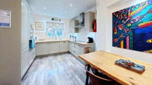 a kitchen with a table and a painting on the wall at The Tidal Shack - Part of the The Bay Filey Holiday Village with pool, gym and direct beach access, pub, restaurant, tennis and meadows walks in Reighton +41 photos