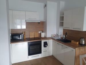a small kitchen with white cabinets and a microwave at Apartament Number One NOVA WOZOWNIA in Leszno