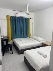 a room with three beds and a blue curtain at Raub Colonial Homestay in Raub +1 photo