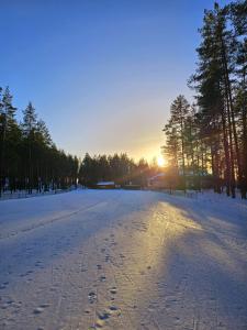an empty road with footprints in the snow at sunset at Alutaguse Tervisespordikeskuse Peamaja in Vasavere