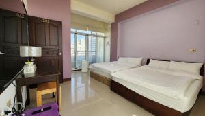 a bedroom with two beds and a desk and a window at Dongle B&B in Taitung City