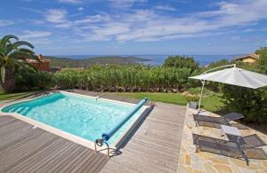 a swimming pool with an umbrella and two chairs and an umbrella at Villa Pierretti - Vue mer Panoramique in Coti-Chiavari