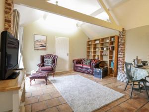 a living room with two chairs and a tv at Ivy Barn in Norwich