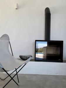 a living room with a white chair and a television at Casa Horizonte in Iznájar