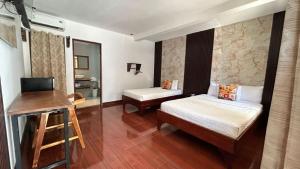 a room with two beds and a desk and a mirror at Hotel Wilson Anexo in Liberia