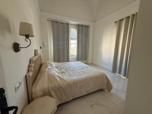 a white bedroom with a bed and a window at Yocca Hotel Residence in Hammamet