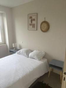 a white bed with two pillows on it in a bedroom at Logis Le Pagnon in Brive-la-Gaillarde
