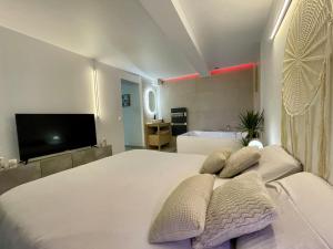a bedroom with a white bed with pillows and a tv at Romantic Suite & Jungle in Longjumeau
