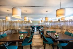 a restaurant with wooden tables and blue chairs at EPIC SANA Luanda Hotel in Luanda