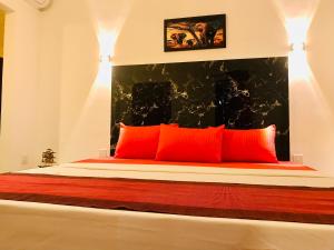 a bedroom with a bed with red pillows at Hasi Villa in Ahungalla