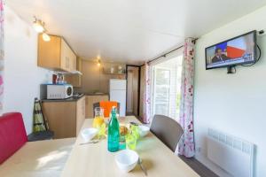 a kitchen with a dining table with a television on the wall at ZEcamping 3 étoiles animaux acceptés avec piscine chauffée à Guérande in Guérande