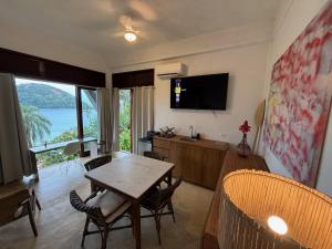 a living room with a table and chairs and a television at Vista para o Mar - Studio com 2 banheiros - Barra do Sahy in São Sebastião