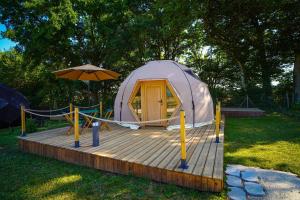 a tent with an umbrella on a wooden deck at L'Orée des 4 chemins in Fontenoy