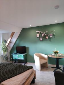 a bedroom with a green wall with a bed and a table at Eider in Karolinenkoog