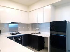 a kitchen with white cabinets and a black refrigerator at Cinnamon Life Residency in Colombo