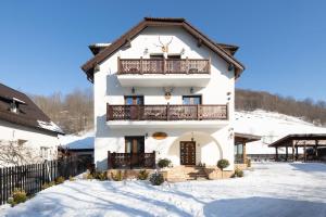 a white house with a balcony in the snow at Branovia in Bran