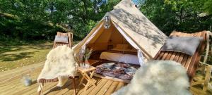 a tent with two chairs and a bed on a deck at Sävö Vandrarhem & Café in Västerljung