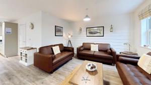 a living room with two leather couches and a table at Old England Cottage - Part of the The Bay Filey Holiday Village with pool, gym and direct beach access, pub, restaurant, tennis and meadows walks in Filey