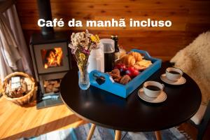 a table with a coffee maker and a tray of food at Cabana Terra - Hidro com vista, Lareira e Café da manhã in Nova Petrópolis