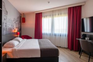 a bedroom with a bed with red curtains and a desk at Bastion Hotel Amersfoort in Amersfoort