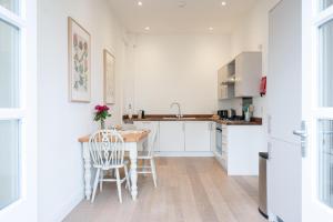 a kitchen with white cabinets and a table and chairs at Ploughman’s Green, Blythburgh in Halesworth