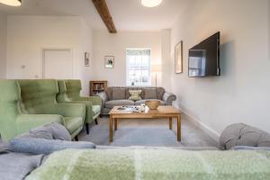 a living room with two couches and a tv at Ploughman’s Green, Blythburgh in Halesworth