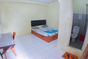 a small bedroom with a bed and a toilet at Wisma Dahlia in Maumere