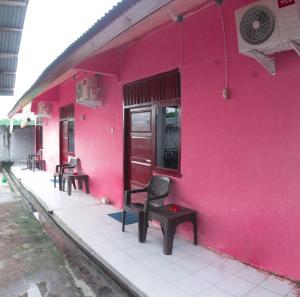 a pink building with chairs and a pink wall at Wisma Dahlia in Maumere