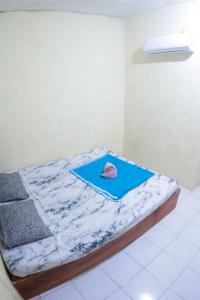 a bed with a blue sheet and a hat on it at Wisma Dahlia in Maumere