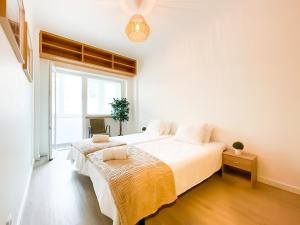 a bedroom with a large white bed with a window at Modern 3 Bedroom Apartment Near Belém Lisbon Upto 5 Guests in Cruz Quebrada