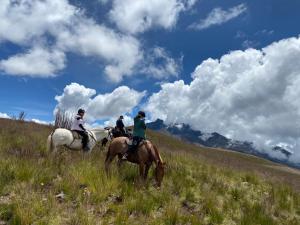 a group of people riding horses in a field at Hacienda La Merced Baja in Hacienda Zuleta