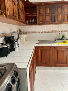 a kitchen with wooden cabinets and white counter tops at Ecopolis Hospedaje en el queremal in Papagalleros