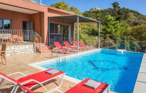 a swimming pool with red chairs and a house at Villa Giorgio by Villa Select in Kefallonia +18 photos
