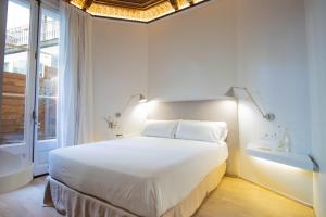 a white bedroom with a large bed and a window at Storni Barcelona by Forget me not in Barcelona