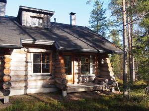 uma cabana de madeira com um alpendre na floresta em Kelomaja Ylläs em Äkäslompolo