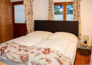 a white bed with a floral blanket on it at Seehütte Tamberger in Feld am See