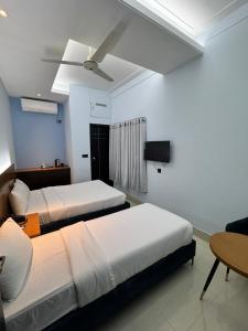 a bedroom with two beds and a ceiling fan at Nessa Inn in Sholāshahar