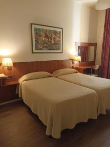 two beds in a hotel room with two lamps at Hotel Europa in Girona