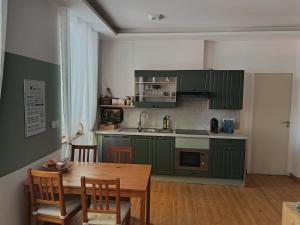a kitchen with green cabinets and a wooden table at Renovated charming appartment in Strasbourg +11 photos